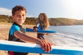Portrait Of Children Wearing Wetsuits Carrying Bodyboards On Summer Beach Vacation Having Fun By Sea Royalty Free Stock Photo