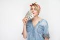 Portrait of chilling beautiful young girl in casual blue denim shirt with makeup and red headband standing ,enjoying the smell of Royalty Free Stock Photo