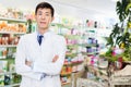 Portrait of chinese man pharmacist who is standing on his work place in apothecary.