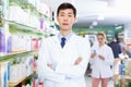 Portrait of chinese man pharmacist who is standing on his work place in apothecary.