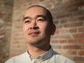 Portrait of chinese young man against red bricks wall background Royalty Free Stock Photo