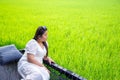 Portrait chubby Asian woman in white dress looking at side lay down on hammock net over the rice field