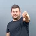 Portrait of chubby young man showing thumb down against gray background Royalty Free Stock Photo