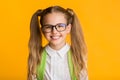 Portrait Of Clever Schoolgirl Smiling At Camera Over Yellow Background