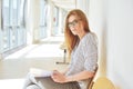 Portrait of clever student with open book reading it in college. Beautiful female student in a university, woman in eyeglasses