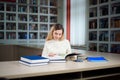 Portrait of clever student with open book reading it in college library. Royalty Free Stock Photo