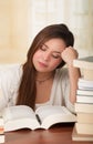 Portrait of clever student with open book reading it in college library falling asleep Royalty Free Stock Photo