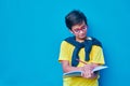 Portrait of a clever and studious boy with red glasses, with a yellow shirt and a sweater on his shoulders, holding a pencil and a Royalty Free Stock Photo