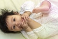 Portrait close up asian cute baby in sleepwear sucking toes after wake up happily on the bed in room Royalty Free Stock Photo