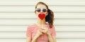 Portrait close up beautiful young woman blowing her lips with red lipstick with red sweet heart shaped lollipop on white Royalty Free Stock Photo