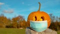 CLOSE UP, COPY SPACE Carved Halloween pumpkin wearing face mask covid protection Royalty Free Stock Photo
