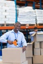 Male staff packing cardboard box with tape gun dispenser in warehouse Royalty Free Stock Photo