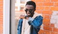 Portrait happy smiling african man with smart watch using voice command recorder or takes calling on a city street