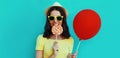Portrait close up happy smiling woman with lollipop and red balloon wearing a summer straw hat on a blue background Royalty Free Stock Photo