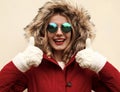 Portrait close up happy smiling woman showing thumbs up as like sign wearing red jacket with fur hood and white mittens Royalty Free Stock Photo