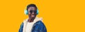 Portrait close up of happy smiling young african man in wireless headphones listening to music looking away isolated on yellow Royalty Free Stock Photo