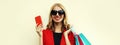 Portrait close up happy smiling young woman with shopping bags showing smartphone wearing a red business blazer on background Royalty Free Stock Photo