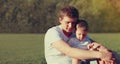 Portrait close up happy young father and son child together sitting on a grass in a park Royalty Free Stock Photo