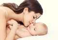 Portrait happy young mother kissing lying her baby on bed at home Royalty Free Stock Photo