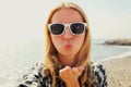Portrait close up happy young woman blowing her lips sending sweet air kiss stretching hand for taking selfie on a sea Royalty Free Stock Photo