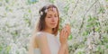 Portrait close up lovely young woman touching petals of flowers wearing a floral headband in a spring blooming garden Royalty Free Stock Photo