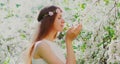 Portrait close up lovely young woman touching petals of flowers wearing a floral headband in a spring blooming garden Royalty Free Stock Photo