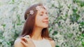 Portrait close up lovely young woman touching petals of flowers wearing a floral headband in a spring blooming garden Royalty Free Stock Photo