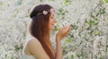 Portrait close up lovely young woman touching petals of flowers wearing a floral headband in a spring blooming garden Royalty Free Stock Photo