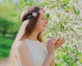 Portrait close up lovely young woman touching petals of flowers wearing a floral headband in a spring blooming garden Royalty Free Stock Photo