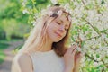 Portrait close up lovely young woman touching petals of flowers wearing a floral headband in a spring blooming garden Royalty Free Stock Photo