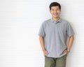 Portrait close up shot of handsome asian male model with short black hair wearing gray polo shirt stand smiling in front of white Royalty Free Stock Photo