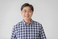 Portrait close up shot of middle aged asian male model with short black hair wearing blue plaid shirt with stand smiling in front Royalty Free Stock Photo