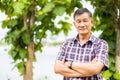 Close-up shot of middle-aged Asian male model with short black hair wearing a plaid shirt with stand smiling in the park Royalty Free Stock Photo