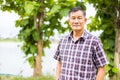 Close-up shot of middle-aged Asian male model with short black hair wearing a plaid shirt with stand smiling in the park Royalty Free Stock Photo