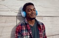 Portrait close up smiling african man in wireless headphones enjoying listening to music on gray wall Royalty Free Stock Photo