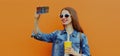 Portrait close up smiling woman taking a selfie picture by smartphone wearing a denim jacket on an orange background Royalty Free Stock Photo