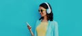 Portrait close up smiling young woman with phone and headphones listening to music on a blue background Royalty Free Stock Photo