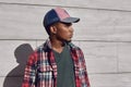 Portrait close up stylish african man looking away wearing baseball cap, red plaid shirt, young guy posing on city street Royalty Free Stock Photo