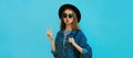 Portrait close up young woman blowing her red lips sending sweet air kiss wearing a black round hat, denim jacket on a blue Royalty Free Stock Photo