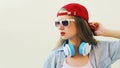 Portrait close up of young woman in red baseball cap and wireless headphones listening to music over white background Royalty Free Stock Photo