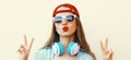 Portrait close up of young woman in red baseball cap and wireless headphones listening to music over white background Royalty Free Stock Photo