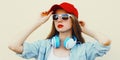 Portrait close up of young woman in red baseball cap and wireless headphones listening to music over white background Royalty Free Stock Photo