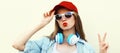 Portrait close up of young woman in red baseball cap and wireless headphones listening to music over white background Royalty Free Stock Photo