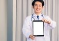 Doctor in uniform and stethoscope neck strap showing front blank screen smart digital tablet on hand