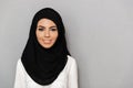 Portrait closeup of muslim prayer woman 20s in religious headscarf smiling and looking at camera, isolated over gray background