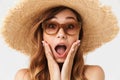 Portrait closeup of shocked or excited woman 20s wearing big straw hat and sunglasses posing on camera with hands on Royalty Free Stock Photo