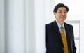 Portrait closeup shot of Asian senior happy success rich ceo corporate director in black formal suit with brown tie standing Royalty Free Stock Photo