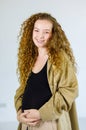 Portrait closeup studio shot of happy healthy curly hairstyle Caucasian pregnancy mother model in casual maternity outfit standing Royalty Free Stock Photo