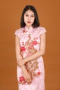 Portrait closeup studio shot millennial Asian female model in pink Chinese cheongsam qipao traditional peacock & flowers pattern Royalty Free Stock Photo