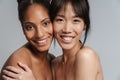 Portrait of two multinational half-naked women hugging and laughing Royalty Free Stock Photo